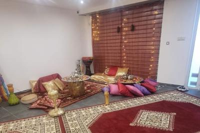 Salon décoré avec des tapis orientaux, un canapé doré, des coussins colorés et des éléments décoratifs traditionnels.