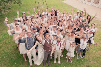 Salle de réception élégante avec tables dressées, chaises blanches et décorations florales sous un éclairage chaleureux.