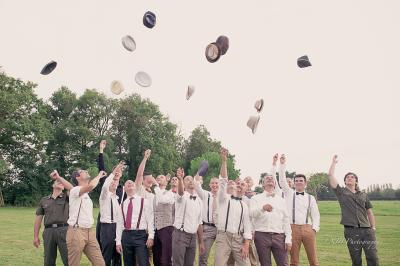 Salle de réception élégante avec tables dressées, chaises blanches et décorations florales sous un éclairage chaleureux.