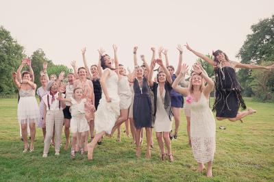 Salle de réception élégante avec tables dressées, chaises blanches et décorations florales sous un éclairage chaleureux.
