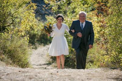 Salle de réception élégante avec tables dressées, chaises blanches et décorations florales sous un éclairage chaleureux.