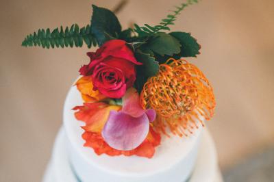 Salle de réception élégante avec tables dressées, chaises blanches et décorations florales sous un éclairage chaleureux.