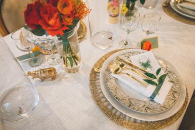 Salle de réception élégante avec tables dressées, chaises blanches et décorations florales sous un éclairage chaleureux.