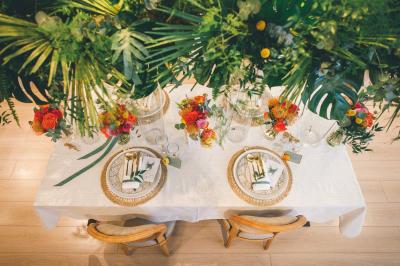 Salle de réception élégante avec tables dressées, chaises blanches et décorations florales sous un éclairage chaleureux.
