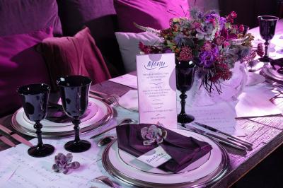 Salle de réception élégante avec tables dressées, chaises blanches et décorations florales sous un éclairage chaleureux.