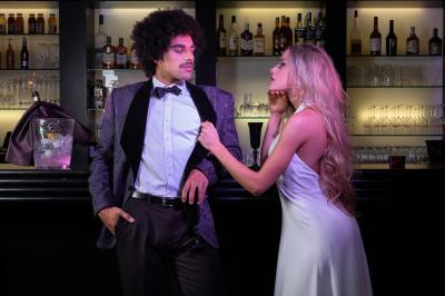 Salle de réception élégante avec tables dressées, chaises blanches et décorations florales sous un éclairage chaleureux.