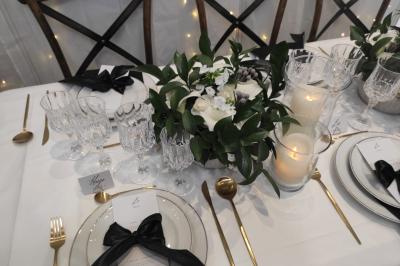 Salle de réception élégante avec tables dressées, chaises blanches et décorations florales sous un éclairage chaleureux.
