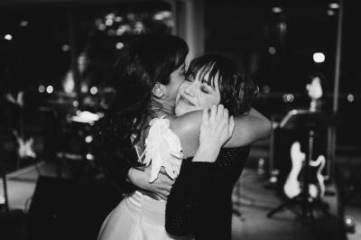 Salle de réception élégante avec tables dressées, chaises blanches et décorations florales sous un éclairage chaleureux.