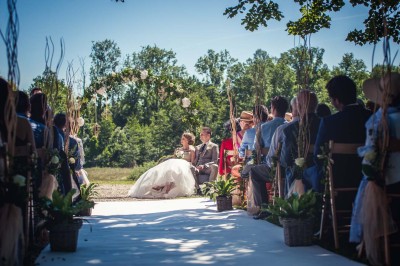 Allée gravillonnée bordée de lanternes blanches menant à un jardin arboré, vue depuis un portail en fer forgé.