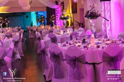 Allée gravillonnée bordée de lanternes blanches menant à un jardin arboré, vue depuis un portail en fer forgé.