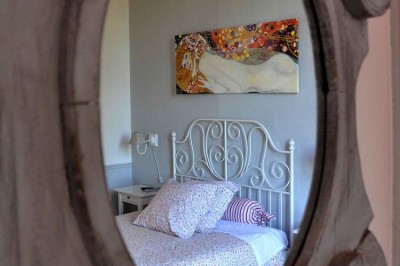 Allée gravillonnée bordée de lanternes blanches menant à un jardin arboré, vue depuis un portail en fer forgé.