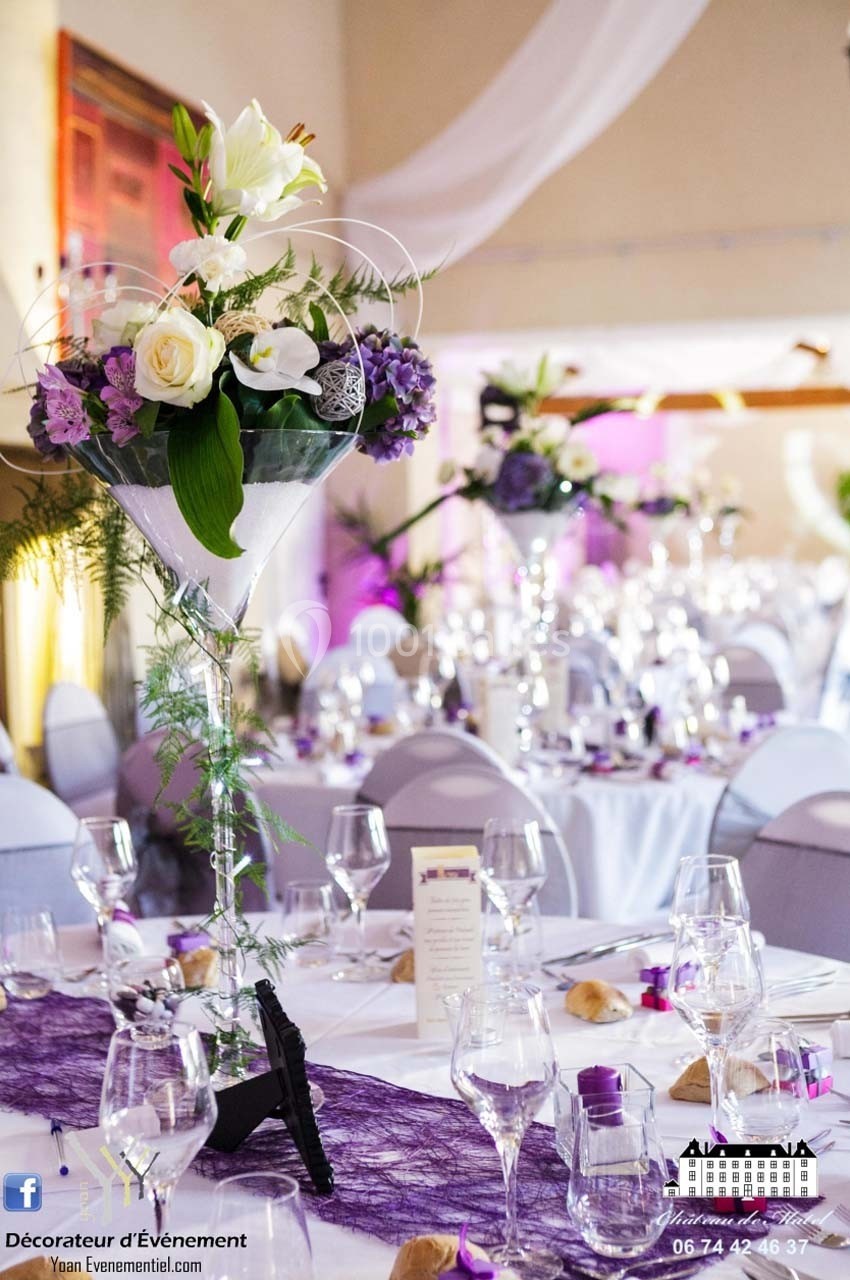 Décoration de table élégante avec fleurs blanches et violettes, nappes blanches et détails en dentelle violette.