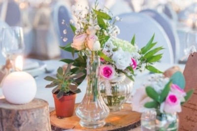 Allée gravillonnée bordée de lanternes blanches menant à un jardin arboré, vue depuis un portail en fer forgé.