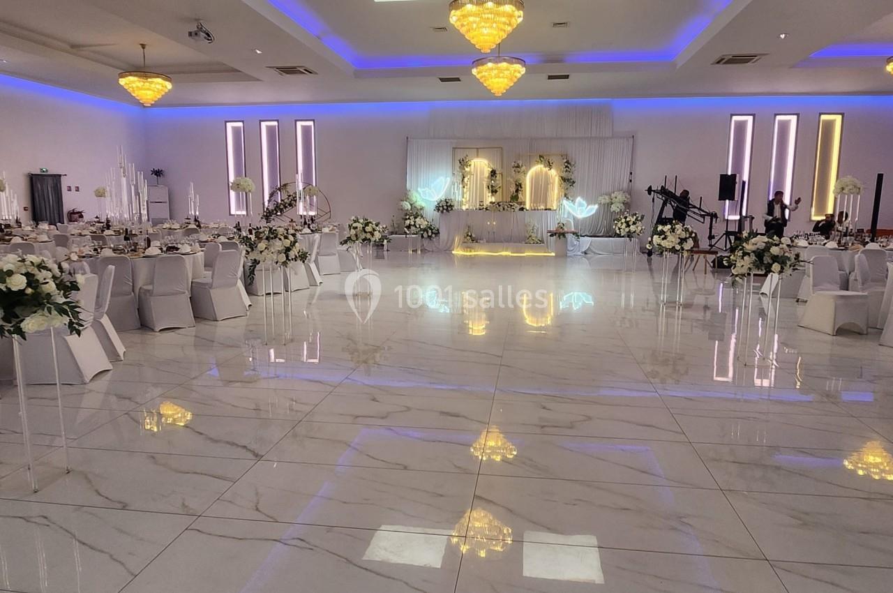 Salle de réception élégante avec tables décorées, sol en marbre brillant et éclairage chaleureux.