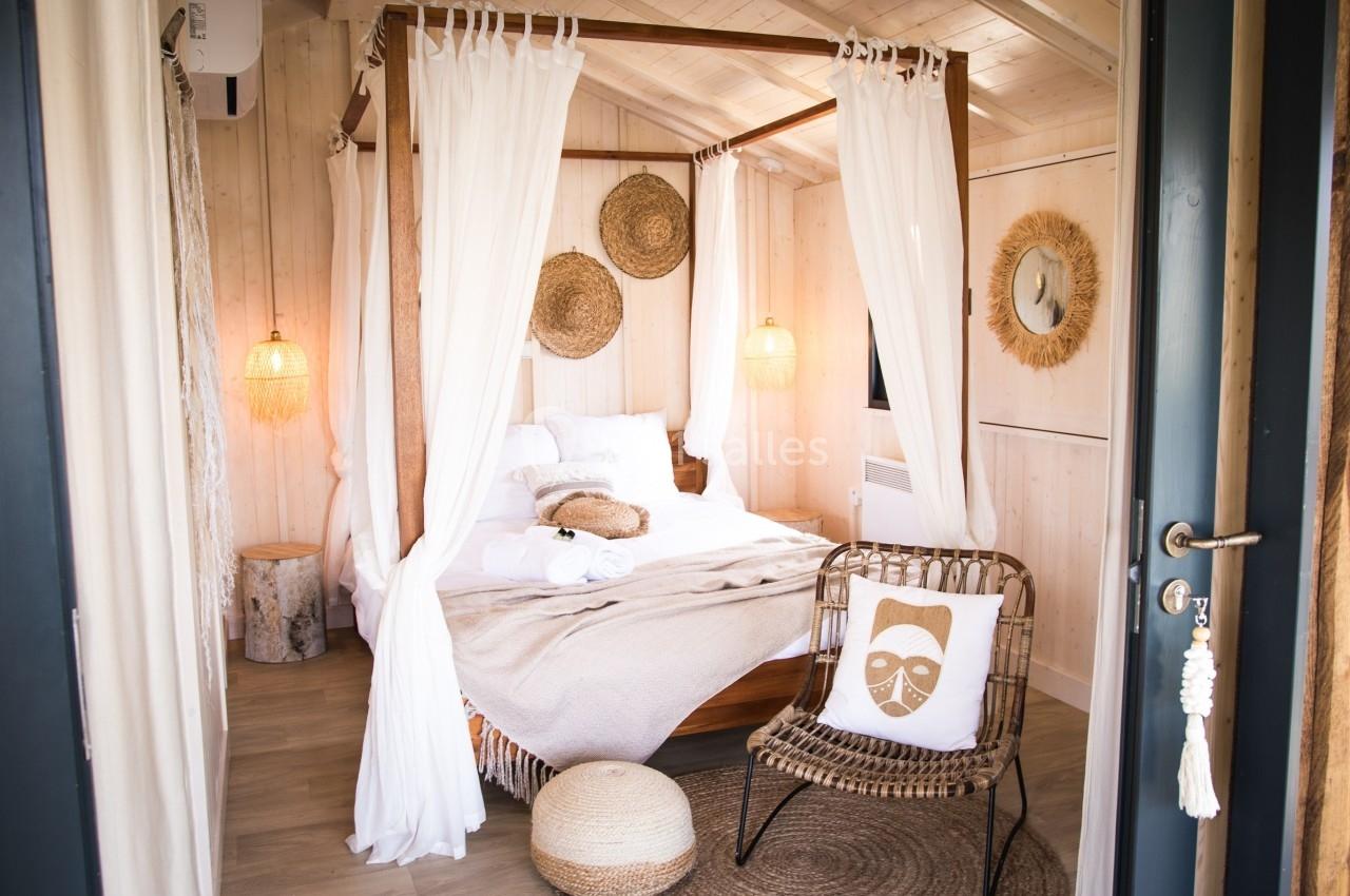 Chambre lumineuse avec lit à baldaquin en bois, décorée de tons naturels et d'éléments en rotin.