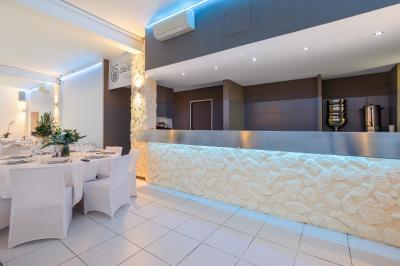 Salle de réception décorée avec des tables rondes, nappes blanches, chaises élégantes et éclairage violet tamisé.