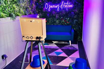 Salle de réception décorée avec des tables rondes, nappes blanches, chaises élégantes et éclairage violet tamisé.