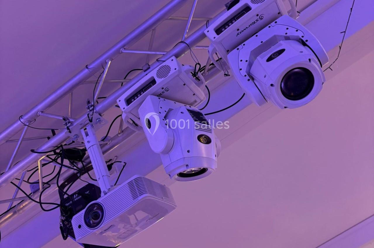 Projecteurs et équipements d'éclairage suspendus à une structure métallique dans un environnement intérieur.