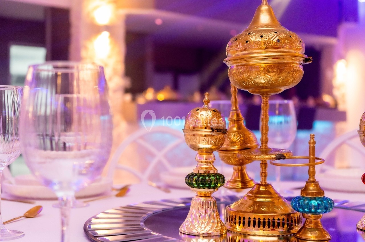 Service à thé oriental doré décoratif sur une table élégante, entouré de verres et d'une lumière tamisée.