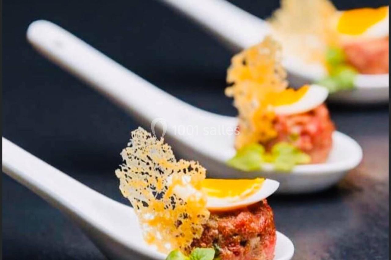 Bouchées gastronomiques servies sur des cuillères en porcelaine, avec œuf, croustillant et herbes fraîches.