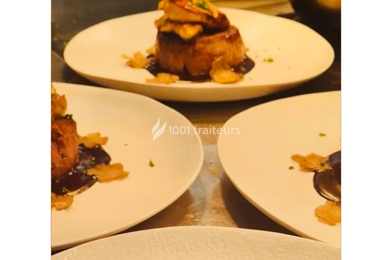 Assiette gastronomique avec un morceau de viande surmonté de garniture, accompagnée de sauce et de chips croustillantes.