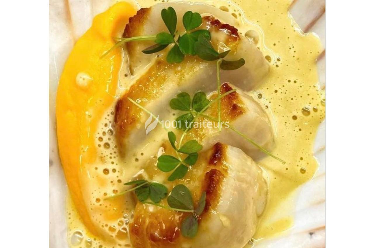Noix de Saint-Jacques poêlées servies avec une purée de légumes orange, une sauce crémeuse et des feuilles de cresson.