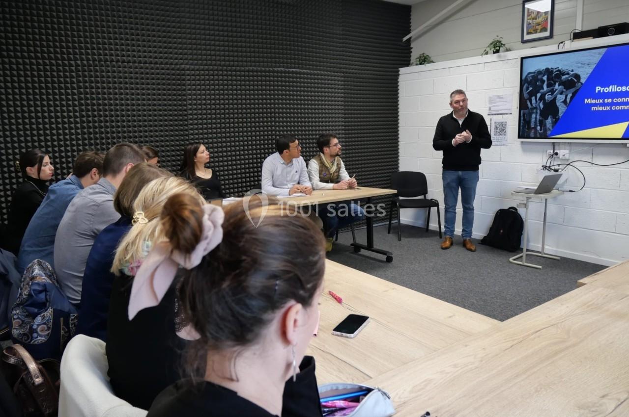 Un homme présente un diaporama à un groupe de personnes assises dans une salle de réunion.