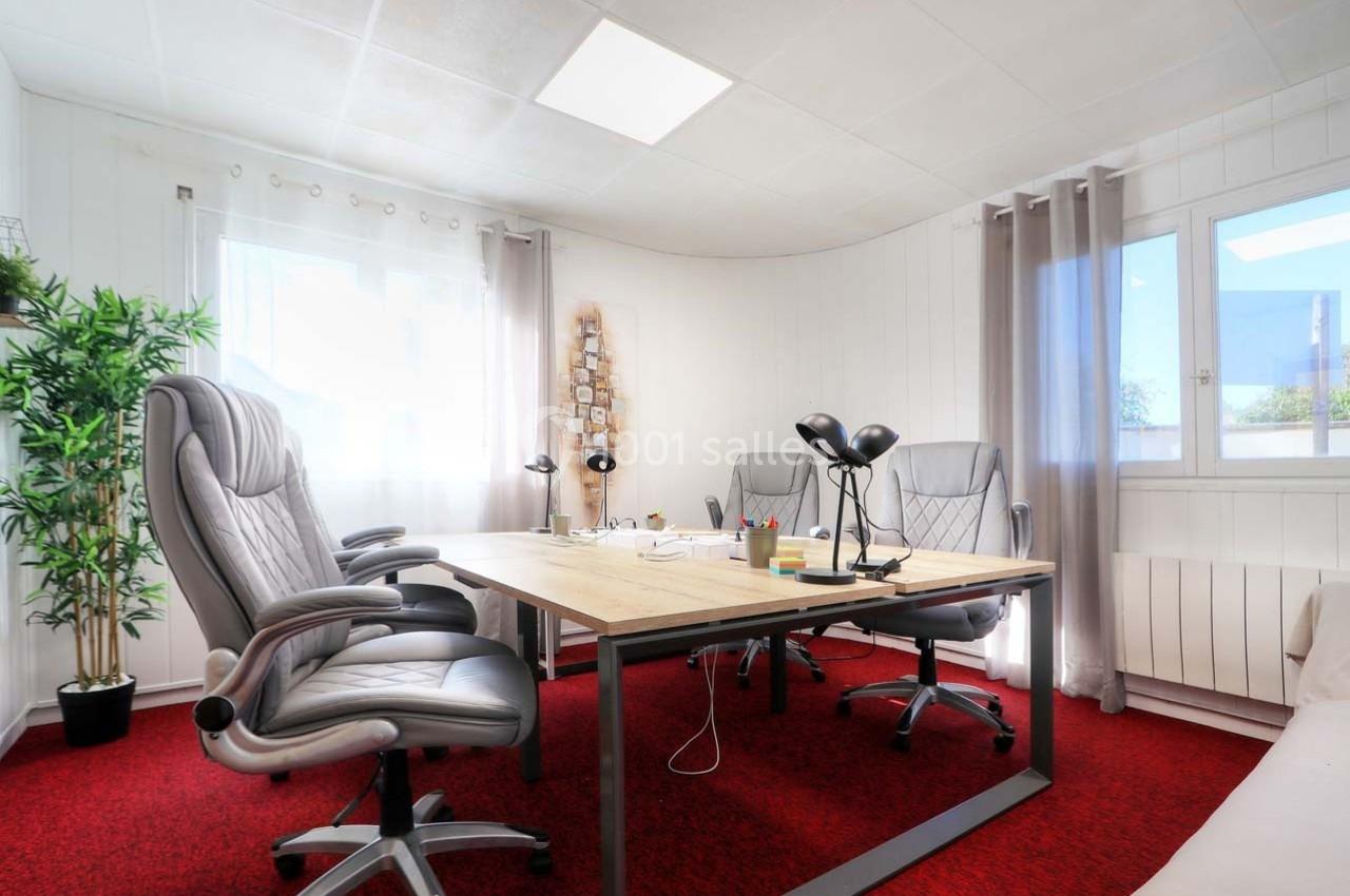Bureau lumineux avec deux fauteuils gris, une table en bois, lampes de bureau et fenêtres laissant entrer la lumière…