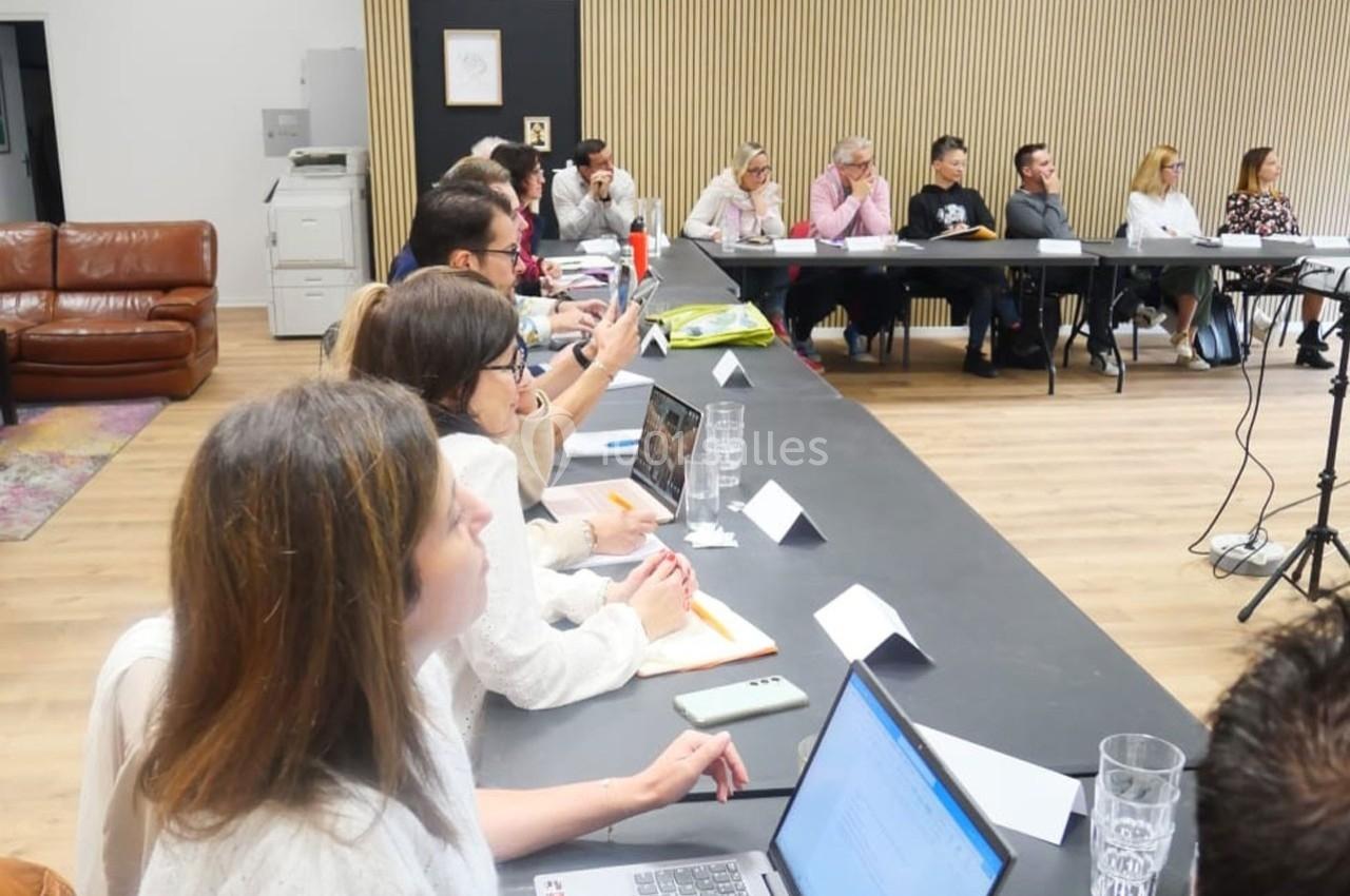 Des personnes assises autour d'une grande table en réunion, certaines prenant des notes ou utilisant des ordinateurs…