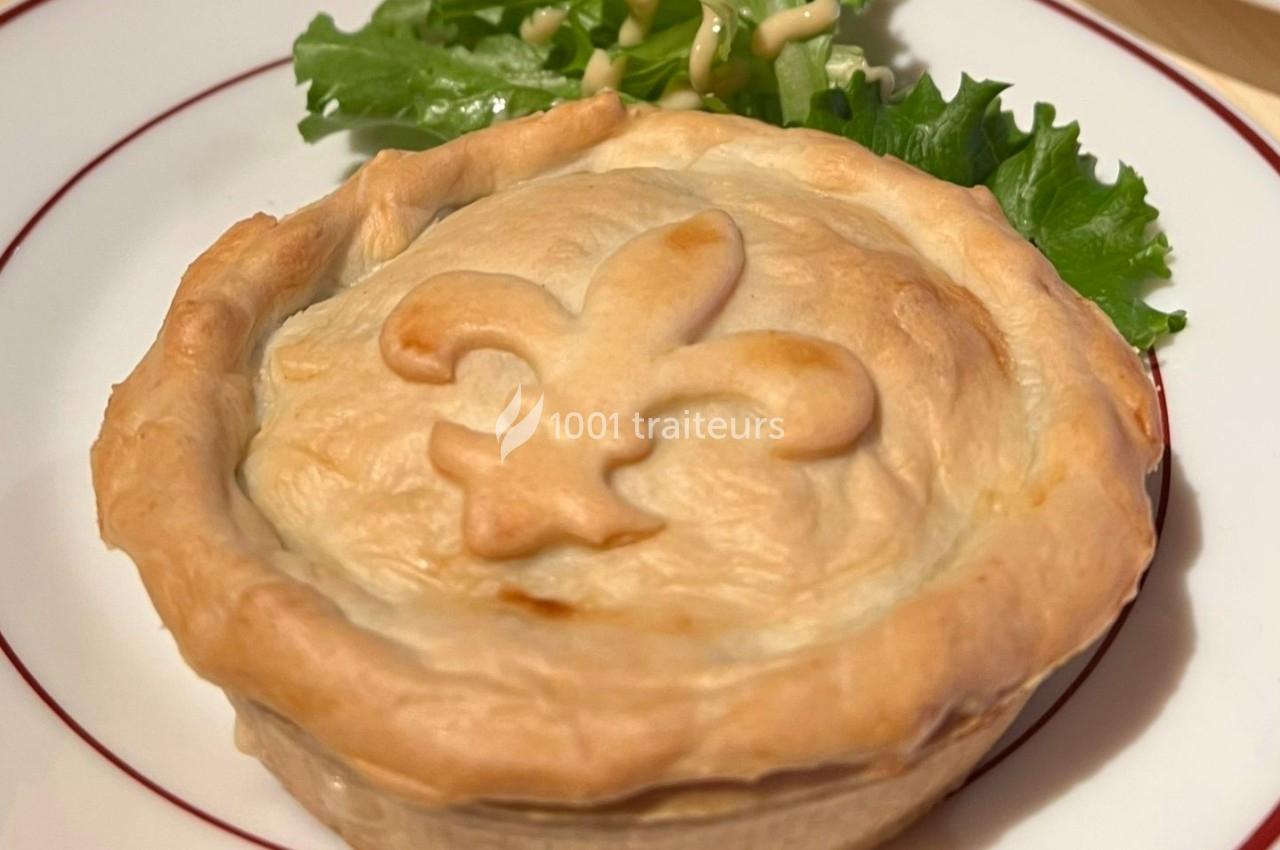 Tourte individuelle dorée avec une fleur de lys en relief sur le dessus, accompagnée de salade verte.