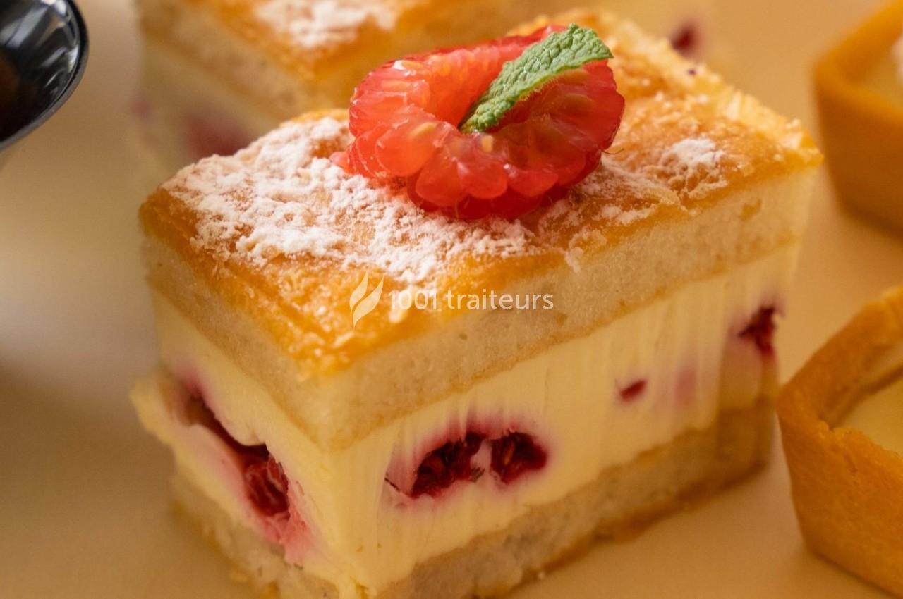 Gâteau à étages avec crème, framboises fraîches, sucre glace et une garniture de framboise et feuille de menthe.