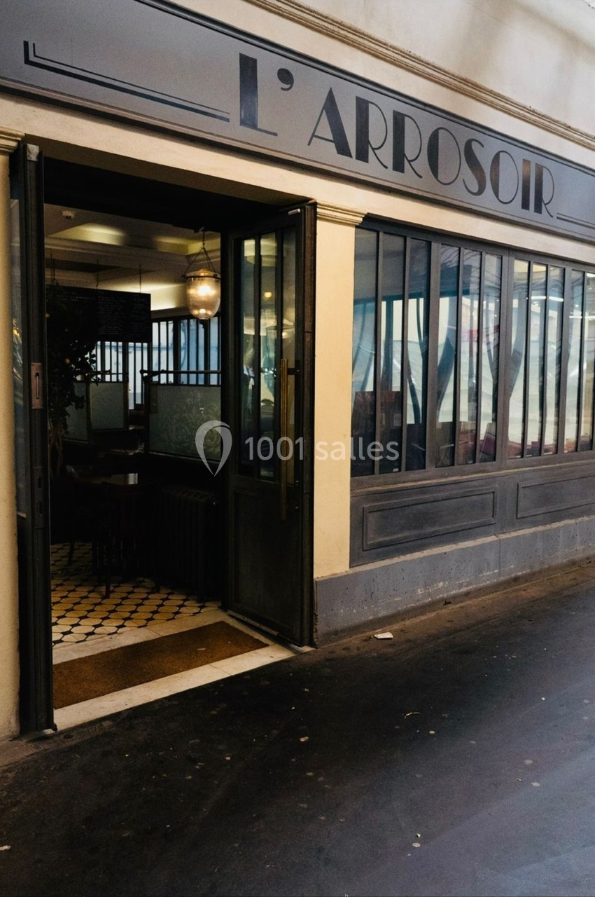 Façade d'un restaurant avec une porte ouverte, des fenêtres vitrées et un intérieur visible avec des tables.