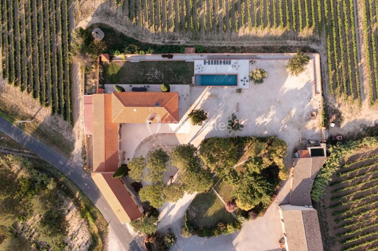 Vue aérienne d'une propriété avec piscine entourée de vignes et de bâtiments annexes dans un cadre rural.