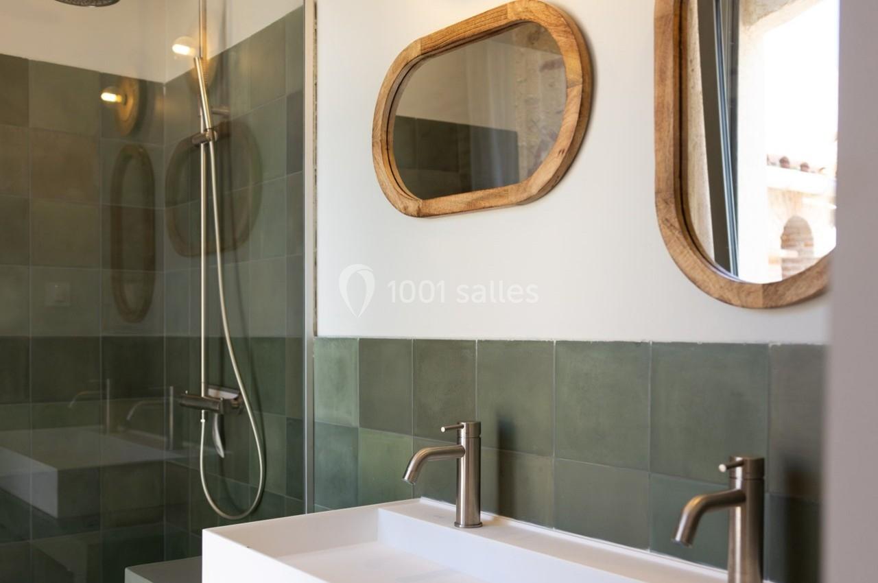Salle de bain moderne avec douche à l'italienne, murs en carreaux verts, double vasque et miroirs en bois.