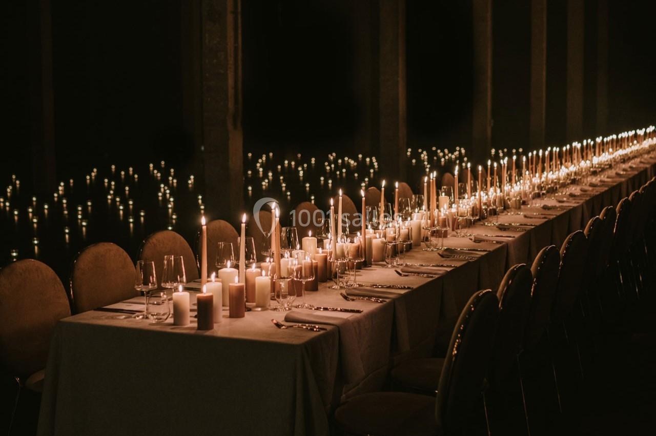 Grande table élégamment dressée avec des bougies allumées, créant une ambiance chaleureuse et tamisée.