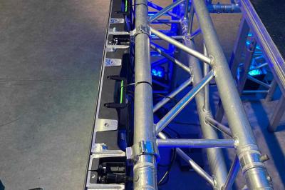 Terrasse en bord de mer avec tables et chaises blanches, vue sur la plage, la mer et un écran affichant une publicité.
