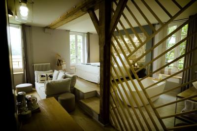 Miniature ALEXANDRINE Chambre lumineuse avec lit double, fauteuil en bois, baignoire blanche et grande fenêtre donnant sur l'extérieur.