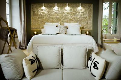 Miniature ALEXANDRINE Chambre lumineuse avec lit double, fauteuil en bois, baignoire blanche et grande fenêtre donnant sur l'extérieur.