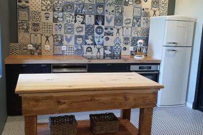 Miniature CUISINE DU MOULIN Chambre lumineuse avec lit double, fauteuil en bois, baignoire blanche et grande fenêtre donnant sur l'extérieur.