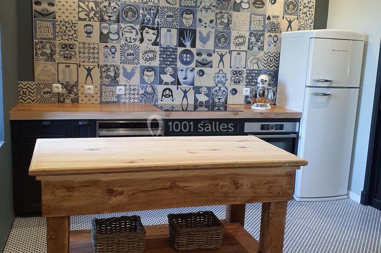 Cuisine avec un îlot en bois, un mur de carreaux décoratifs bleus et blancs, et un réfrigérateur rétro blanc.