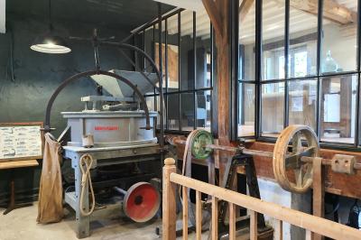 Miniature LA MEULE DE LA SALLE DES MACHINES Chambre lumineuse avec lit double, fauteuil en bois, baignoire blanche et grande fenêtre donnant sur l'extérieur.