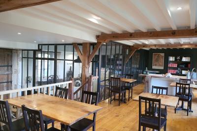 Miniature LA SALLE DU MOULIN ET SA VERRIERE ACIER Chambre lumineuse avec lit double, fauteuil en bois, baignoire blanche et grande fenêtre donnant sur l'extérieur.