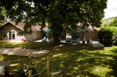 Miniature LA TERRASSE DU PAVILLON Chambre lumineuse avec lit double, fauteuil en bois, baignoire blanche et grande fenêtre donnant sur l'extérieur.
