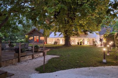 Miniature LE BARNUM SUR LA TERRASSE DU PAVILLON Chambre lumineuse avec lit double, fauteuil en bois, baignoire blanche et grande fenêtre donnant sur l'extérieur.
