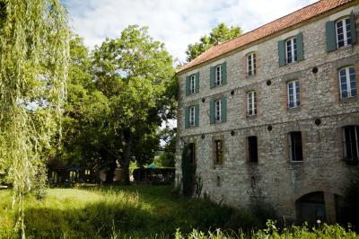 Miniature LE MOULIN CôTE OUEST Chambre lumineuse avec lit double, fauteuil en bois, baignoire blanche et grande fenêtre donnant sur l'extérieur.