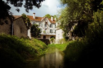 Miniature LE MOULIN ET SON BIEF Chambre lumineuse avec lit double, fauteuil en bois, baignoire blanche et grande fenêtre donnant sur l'extérieur.