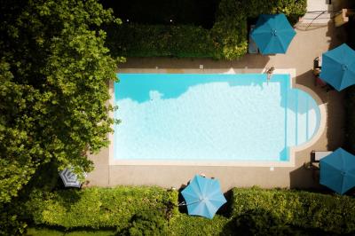 Miniature PISCINE 6X12m Chambre lumineuse avec lit double, fauteuil en bois, baignoire blanche et grande fenêtre donnant sur l'extérieur.