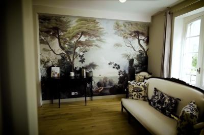 Miniature SUITE EUGENIE SALON COMMUN Chambre lumineuse avec lit double, fauteuil en bois, baignoire blanche et grande fenêtre donnant sur l'extérieur.