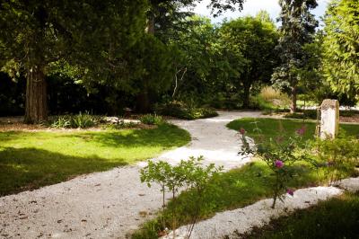 Miniature VERS LE PARKING A TRAVERS LE JARDIN Chambre lumineuse avec lit double, fauteuil en bois, baignoire blanche et grande fenêtre donnant sur l'extérieur.