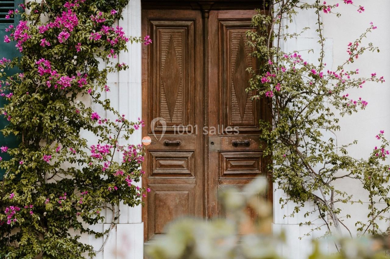 Porte en bois sculpté encadrée de murs blancs et de bougainvilliers fleuris.